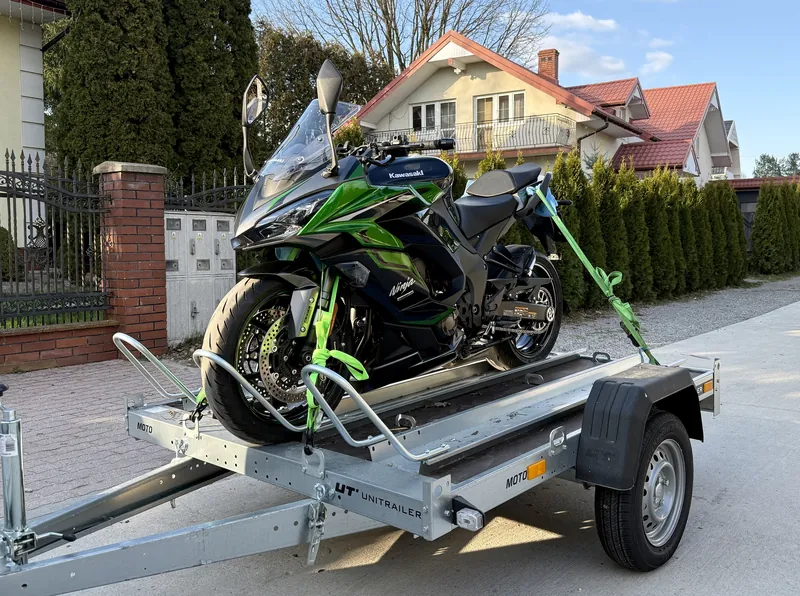 Motocykl Kawasaki Ninja spięty pasami na przyczepce motocyklowej