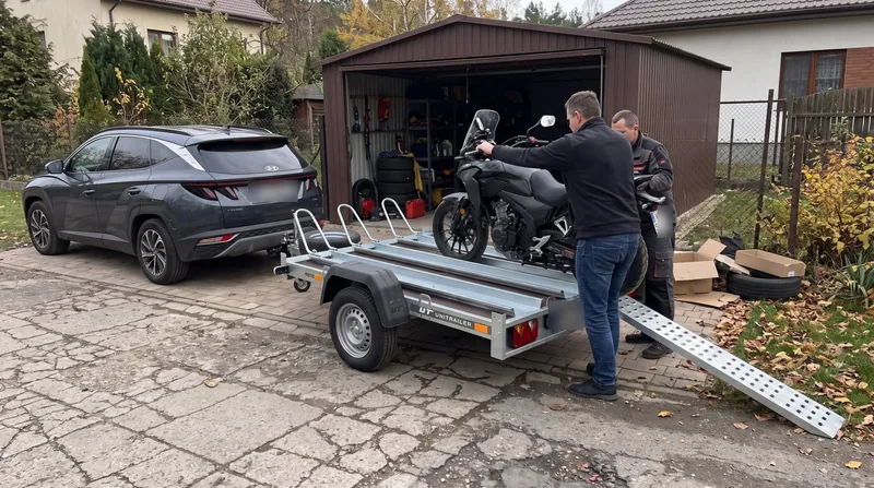 Załadunek kupionego motocykla na przyczepkę pod garażem sprzedającego
